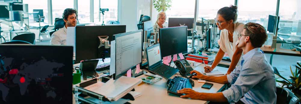 Two employees discussing something over their workspace