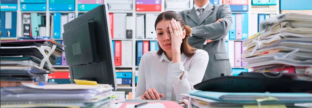 Employee looking frustrated as her manager looks over her shoulder