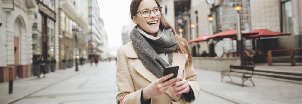 Woman wearing a scarf taking a walk outside with a phone in her hand