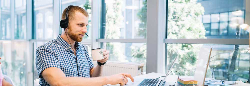 Sales person with a headset working on his laptop